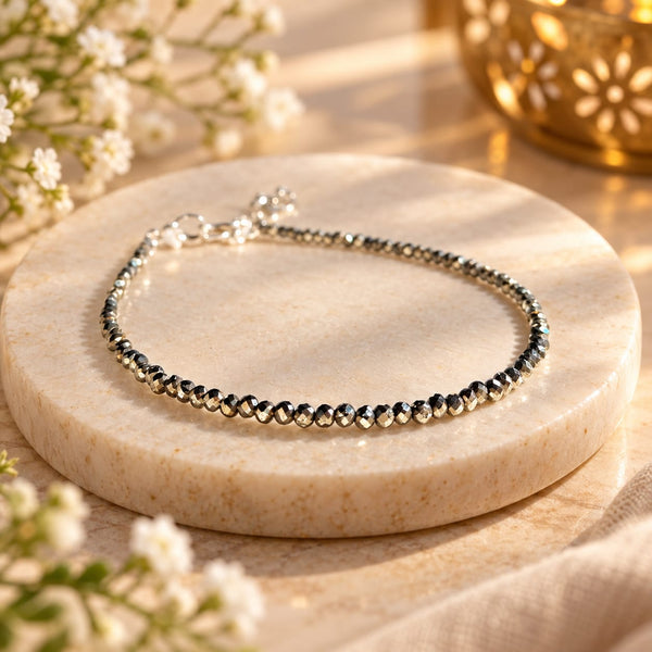 Natural raw Pyrite anklet displayed on a stone platform with premium spiritual styling