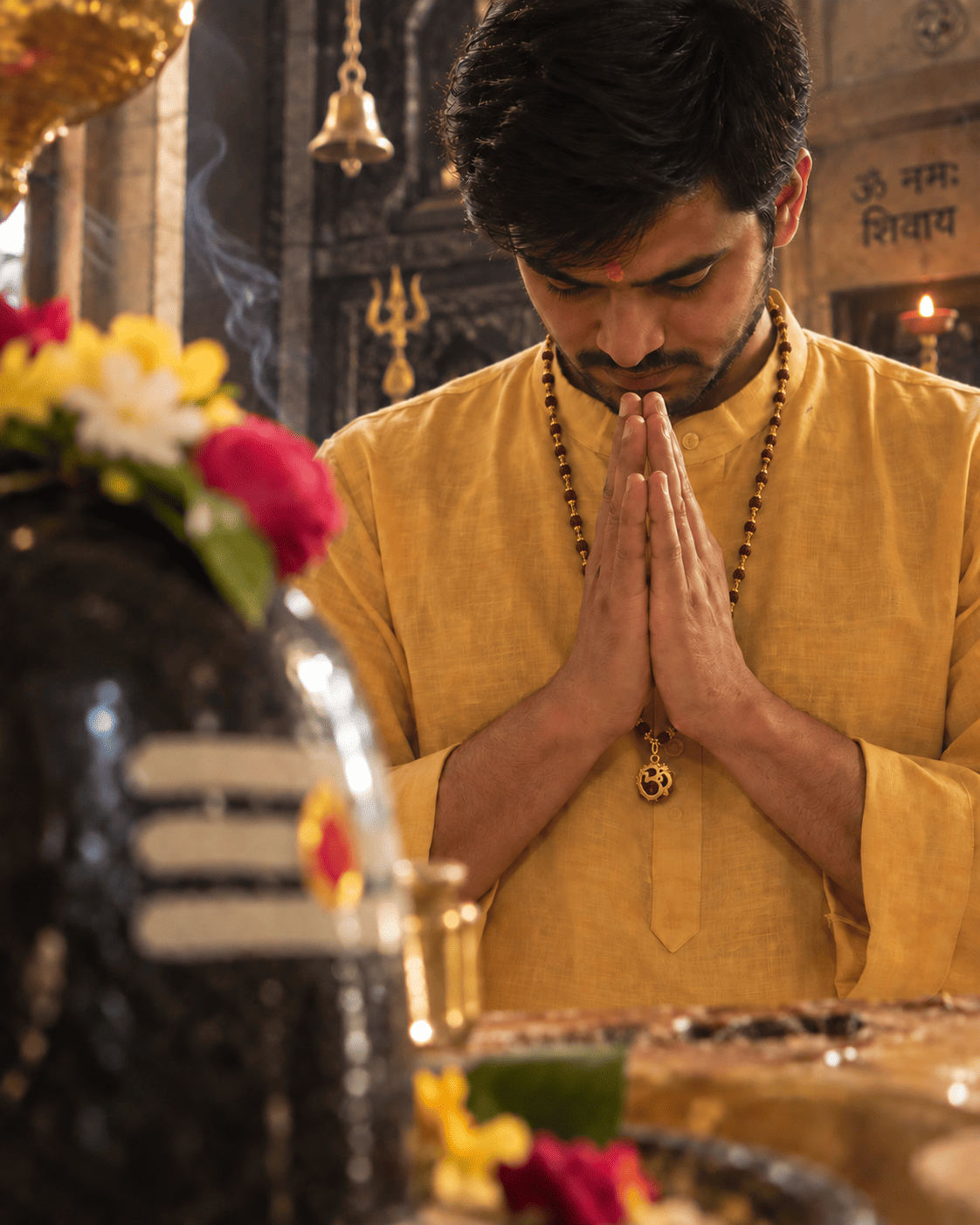 Man wearing a natural 5 Mukhi Rudraksha mala with Om pendant while offering prayers inside a traditional temple