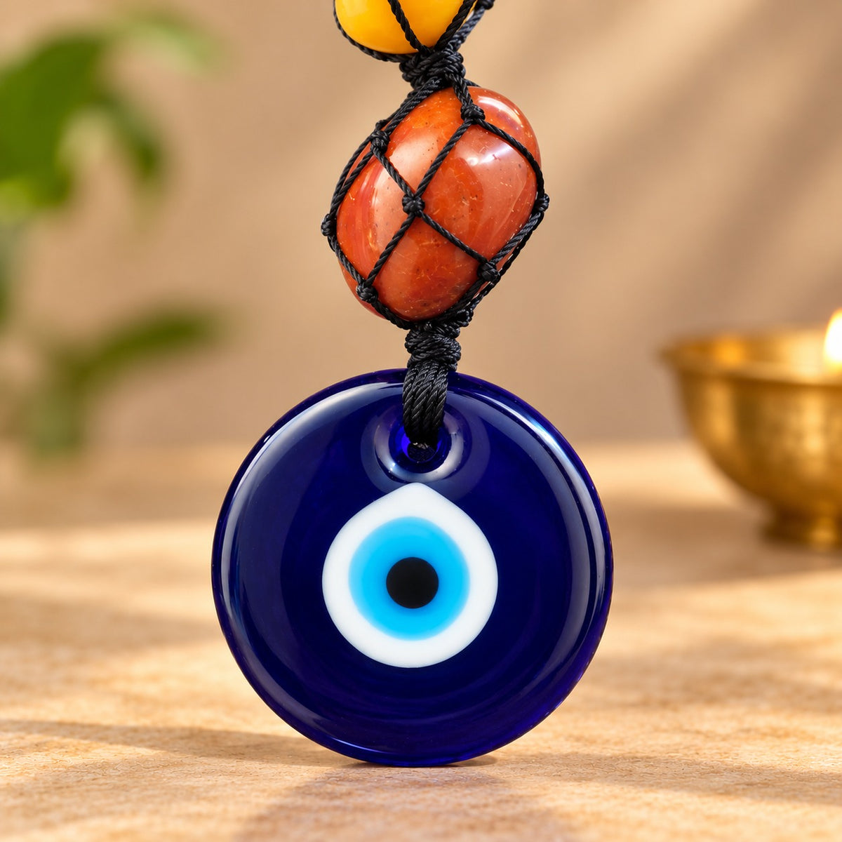 Close-up of blue evil eye pendant with colorful chakra crystal beads in black macrame netting