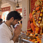 Indian man wearing a gold plated Karungali mala with Hanuman pendant during a devotional visit to a temple.