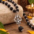 Karungali Mala held in hand showing the natural black ebony beads, silver detailing and Om Shiva Trishul pendant clearly