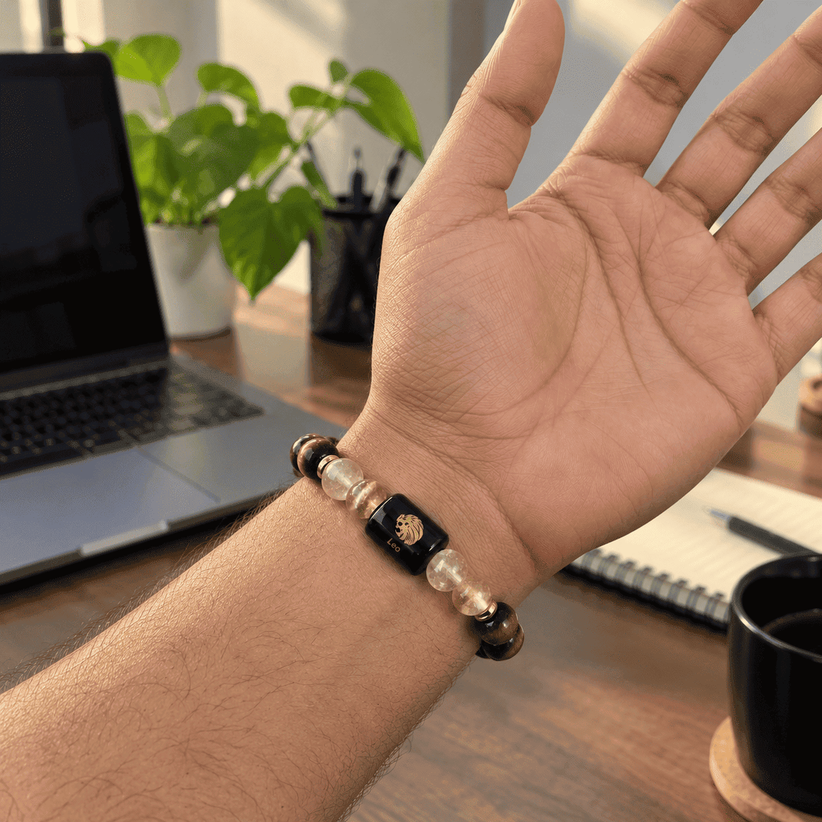 Leo zodiac bracelet worn on an open hand featuring Tiger Eye, Citrine and Leo engraved charm