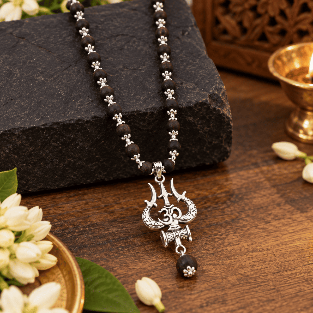 Close-up view of natural Karungali beads with silver floral caps and detailed Om Shiva Trishul pendant