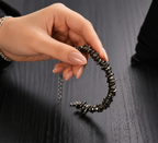 Pyrite Stone Splash Bracelet held by a woman with natural dark metallic pyrite chips and silver adjustable chain