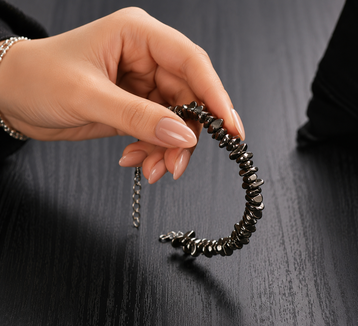 Pyrite Stone Splash Bracelet held by a woman with natural dark metallic pyrite chips and silver adjustable chain